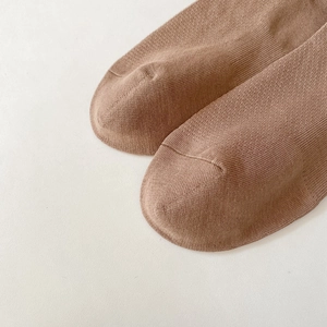 Macro detail of brown knitted socks showing seamless toe seam and breathable mesh texture
