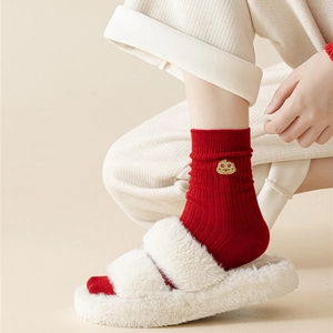 Detail of red cotton socks with gold cartoon embroidery paired with plush slippers