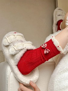 Detail of red knit socks featuring a checkered bow and heart embroidered scalloped cuffs