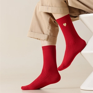 Detail of red crew socks with gold heart embroidery and ribbed cotton texture