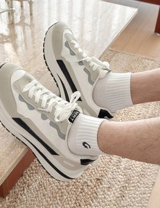Close-up of sporty thick-soled men's sneakers with gray patchwork and G-letter socks