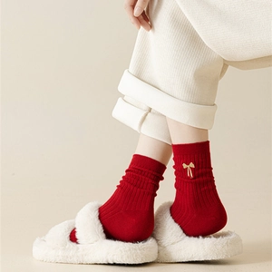 Detail of red cotton socks with gold bow embroidery paired with plush slippers