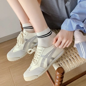 Gros plan de baskets blanc cassé avec chaussettes en fibre de bambou sur parquet