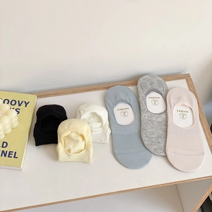 Close-up of cotton non-slip invisible socks in six pastel colors on white wood surface