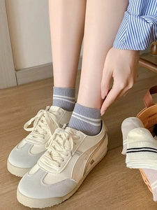 Détail de chaussettes en fibre de bambou à rayures avec baskets rétro sur parquet