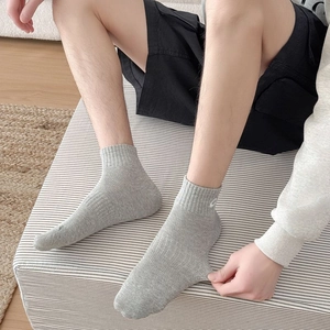 Close-up of grey ribbed knit mid-calf crew sock on foot with G letter embroidery detail