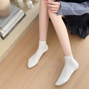 Dettaglio ravvicinato di calze a coste in cotone bianco con ricamo blu su parquet