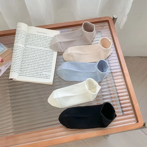 Set of five colorful ribbed bamboo fiber low cut ankle socks on a wooden tray with a book