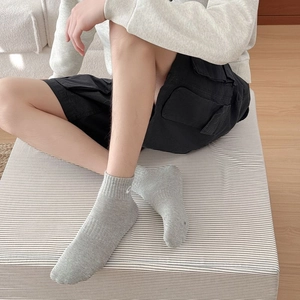 Detail of grey cotton sports socks with white logo on a model wearing casual wear