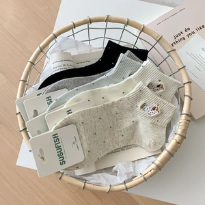 Detailed view of breathable cotton socks with cute dog embroidery in a woven basket