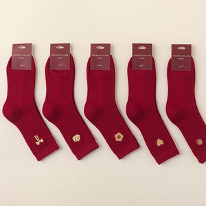 Five pairs of red cotton socks with gold zodiac embroidery in festive gift packaging