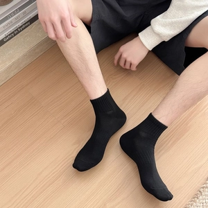 Close-up of black cotton crew socks with ribbed cuffs and breathable mesh texture