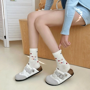 Detail of white cotton sock featuring colorful polka dots and nice day embroidery
