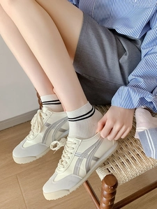 Gros plan de baskets rétro crème avec rayures grises et chaussettes à rayures noires