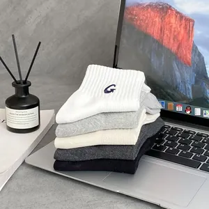 Detail of five pairs of ribbed cotton socks with G embroidery on a laptop surface