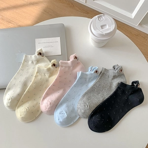 Close-up of 6 colorful polka dot ankle socks with cute dog embroidery on a white table