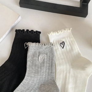 Close-up of cotton socks featuring ruffle cuffs and delicate heart embroidery details