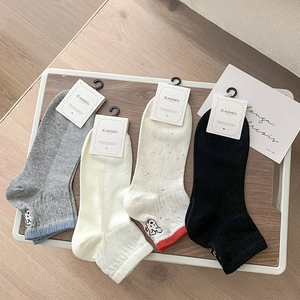 Detail of four pairs of combed cotton socks with dog embroidery on a wooden tray