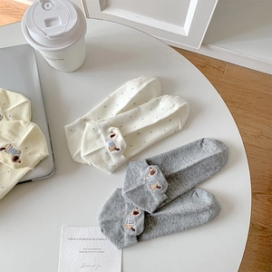 Close-up of white and grey cotton socks featuring polka dots and dachshund embroidery