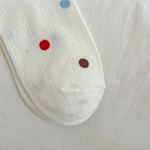 Detailed close-up of white breathable mesh socks featuring colorful polka dot patterns