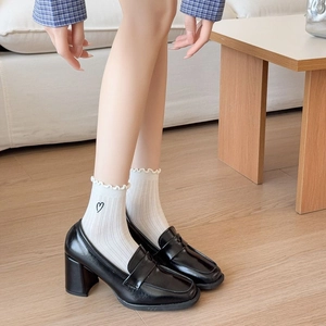 Detail of white ruffle socks paired with black patent leather loafers for a preppy look