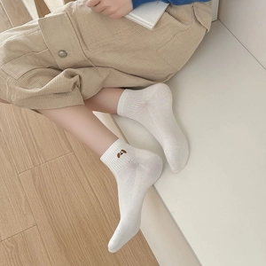 Detailed close-up of white mesh socks with cute dog embroidery on a person wearing corduroy