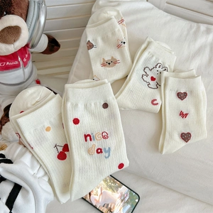 Detail of cream cotton socks featuring cute cherry and bear embroidery in soft lighting