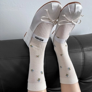 Détail de chaussettes vintage à fleurs et ballerines en satin blanc avec ruban logo