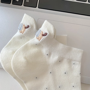 Close-up of white cotton socks with dark polka dots and cute animal embroidery details