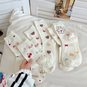 Close-up of cream cotton socks featuring cute cherry, heart, and rabbit patterns