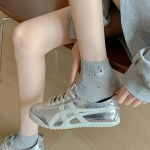Detail of grey cotton sock featuring cute dachshund embroidery paired with silver sneakers