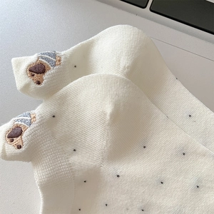 Detail of white cotton ankle sock featuring black polka dots and cute dog heel embroidery