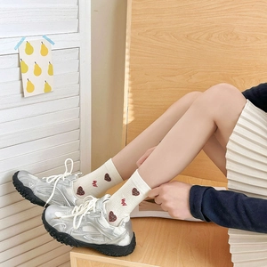 Detail of cream crew socks with red hearts and wavy embroidery paired with silver sneakers