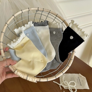 Détail de chaussettes multicolores en coton avec bord à volants et breloque coeur