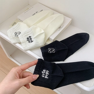 Detailed close-up of cute puppy embroidery and text on cotton socks in black and off-white