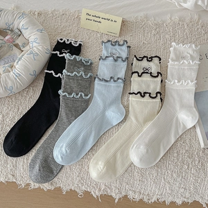 Detail of five pairs of pastel socks with ruffles, bow embroidery, and vertical textures