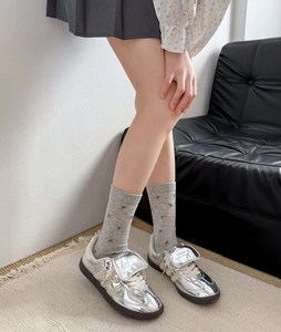 Détails de baskets métalliques argentées avec chaussettes brodées sur tapis beige