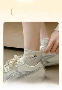 Gros plan d'une chaussette en coton beige avec broderie chiot et bord-côte élastique