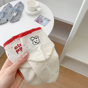Close-up of white cotton socks with cute puppy embroidery and red contrasting trim