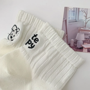 Close-up of white ribbed cotton sock featuring cartoon dog and te py letter embroidery