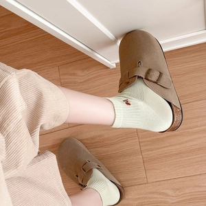 Close-up of brown suede mule shoes with cork sole and adjustable bronze buckle