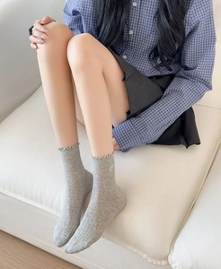 Detail of light gray ribbed socks featuring ruffled edges and small heart embroidery