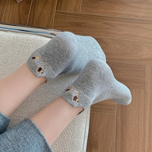 Short light gray cotton socks with dachshund embroidery on woven chair and wood floor