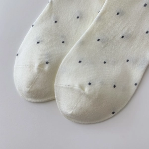 Close-up of white cotton socks with polka dot pattern and ribbed knit texture