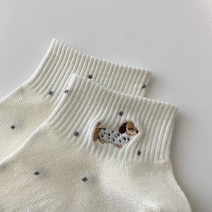 Detailed close-up of white ribbed cotton socks featuring cute puppy embroidery and polka dots