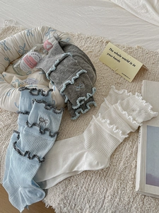 Detail of three pairs of cotton slouch socks with lace ruffles and bow embroidery