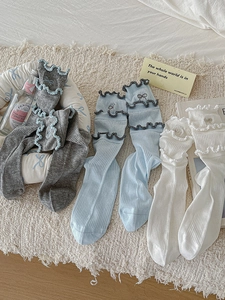 Close-up of three pairs of ruffled crew socks with bow details on plush carpet