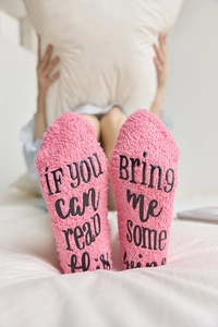 Detail of pink coral fleece socks with funny letter print on soles for lounging