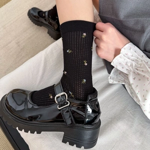 Gros plan de chaussettes noires avec broderies florales et chaussures Mary Jane