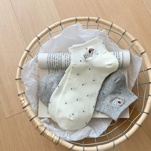 Close-up of cotton ankle socks with cute puppy embroidery and polka dots in a basket